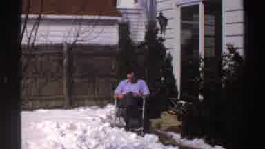 Michigan (1969): A Man Sits In His Backyard Which Is Covered In Snow And Reads In