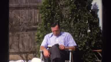 Michigan (1969): Man Sitting In Backyard Of House With Fence And Trees In The