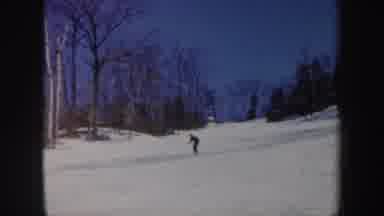 Vermont (1962): A Person In A Black Suit And White Cap Skiing On The Snow On A