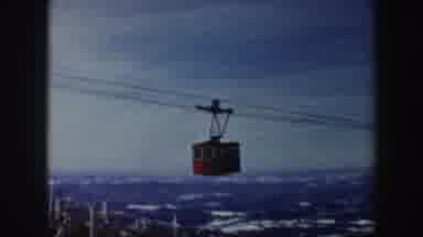 Vermont (1962): Middle-Aged Man Skis While A Red Cable Car Passes Over Him