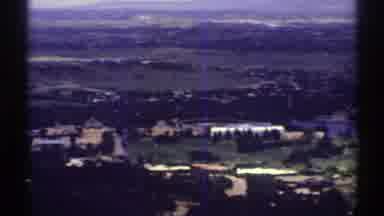 Colorado (1969): View Of Tan Buildings Green Trees And Fields On A Clear Day