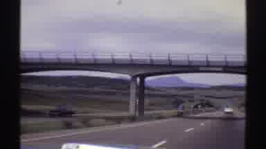 Colorado (1969): Driving Down A Two-Lane Highway Under An Overpass Following A