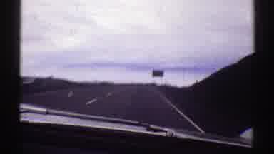 Colorado (1969): Car Driving On The Highway Passing A Green Sign Marked As An