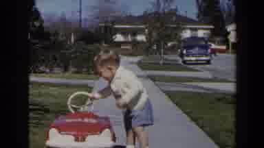 Las Vegas (1958): Toddler Wearing White Sweater Tries Climbing Into Red Toy Car On