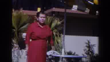 Las Vegas (1958): Woman Wearing Red Dress Stands Near Two Palm Trees On A Sunny