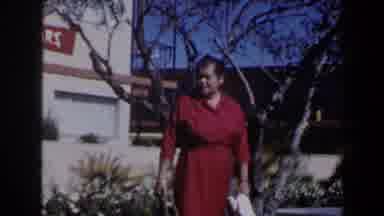 Las Vegas (1958): Woman Wearing Red Dress Walks Past Bare Tree On A Sunny Day