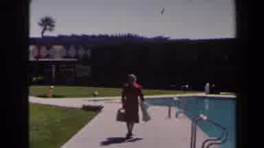 Las Vegas (1958): Woman Wearing Red Dress Walks Past Blue Swimming Pool On A Sunny