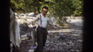 Chelan Washington (1939): Man Wearing Tan Pants Holds Up Grey Fish On A Clear Day
