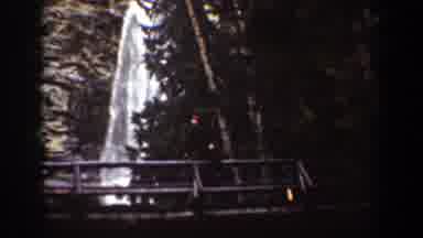Chelan Washington (1939): Man On Top Of Bridge Waving With Waterfall In The