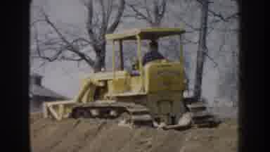 Nebraska (1959): Yellow Tractor Plowing A Mound Of Dirt In A Straight Line