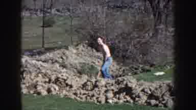Nebraska (1959): Person Wearing Blue Pants Shovels Dirt On A Sunny Day