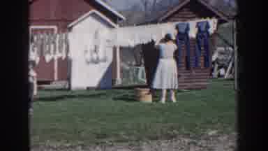 Nebraska (1959): Woman Wearing White Dress Hangs Laundry On Clothesline On A