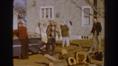Nebraska (1959): People Loading Wood Onto Blue Truck On A Sunny Day