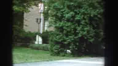 Nebraska (1959): Man Walking In Front Of Industrial Building With Banner That Says