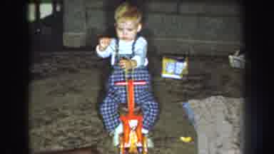 Nebraska (1959): Toddler Boy In Blue Plaid Overalls Playing On Wooden Rocking