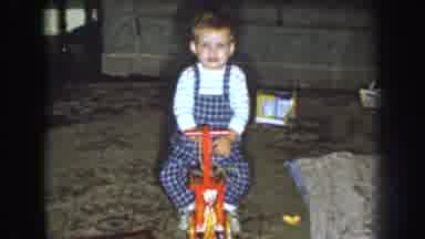 Nebraska (1959): The Toddler Boy Wearing Overalls Happily Sits On A Classic Wooden