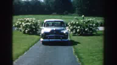 Nebraska (1959): A Gray Car Stopping On A Garden Street And Two Men Come Down