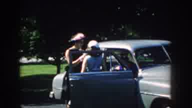 Nebraska (1959): Women Standing Next To Car With Wooded Park In The Background