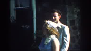 Nebraska (1959): Couple Walks Past White Windows Of Grey Stone House On A Sunny