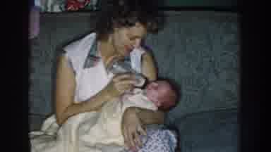 Nebraska (1959): Lady On Blue Couch With Plaid Collar Feeding A Newborn Baby