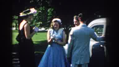 Nebraska-1959: Four People In Formal Wear Stand Near Classic Car On Sunny Day