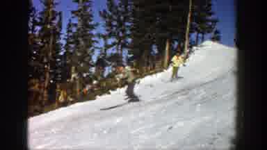 Aspen Colorado (1961): Two People Skiing Down A Snow Covered Hill With Trees In