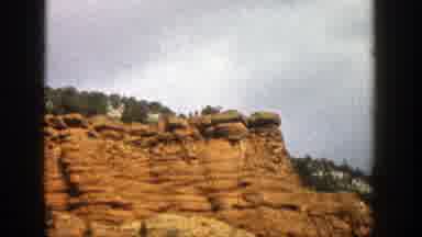 Aspen Colorado (1961): Jagged Tall Rock Wall Cliff With Green Trees And Hills In