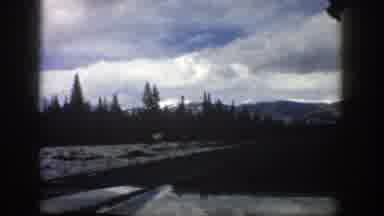 Aspen Colorado (1961): Vehicle Drives Down Road With Curve Mountains In Distance