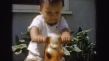 California (1952): Toddler Wearing White Shirt Plays On Brown Toy Horse On A