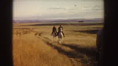 Idaho (1955): Two Men Riding White Horses In A Field With Mountains