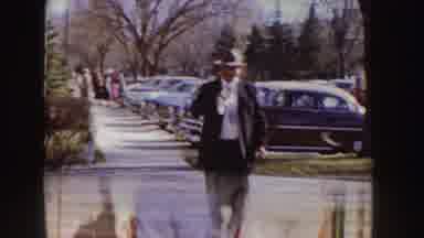 Idaho (1955): Nurses Wearing Black Capes Walk Towards Tan Stone Building On A