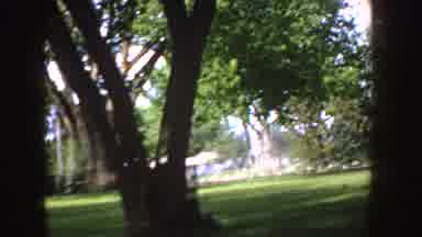 Idaho (1955): Old-Fashioned Car And Man In Orange Shirt Run Through Park At
