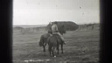 Montana-1939: Two People Ride Horses Through Muddy Field On A Cloudy Day