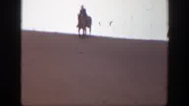 Montana (1939): Person Rides Brown Horse Through Sand On A Cloudy Day