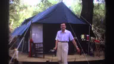 Sudan (1969): A Man Walking Out Of A Tent In A Wooded Area Smiling At The Camera