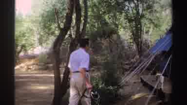 Sudan (1969): Man In White Shirt And Khaki Pants Showing A Tent In The Woods