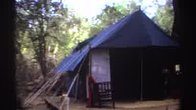 Sudan (1969): A Man Stands Next To A Tent Set Up On A Wooden Platform In A Forest