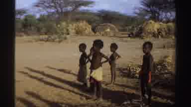 Sudan (1969): People Wearing White Shirts Dance Near Green Trees On A Clear Day