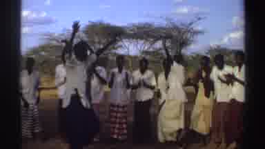 SUDAN-1969: People Wearing White Shirts Dance in Brown Field on a Clear Day