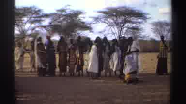 Sudan (1969): In Outdoor Grassy Area White-Dressed Woman Jumps In Group Wearing