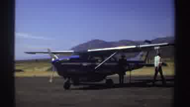 Sudan (1969): Person Wearing White Shirt Walks Around Blue And White Plane On A