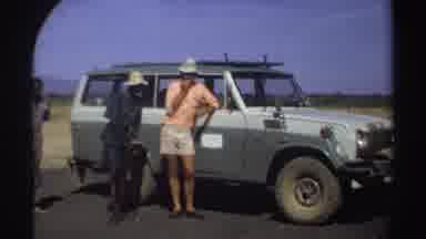 Sudan (1969): Three Men Standing Near A Vehicle On A Sunny Day