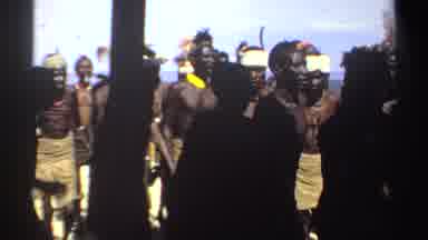 Sudan (1969): A Large Group Of African Men Walk In Formation Wearing Feather