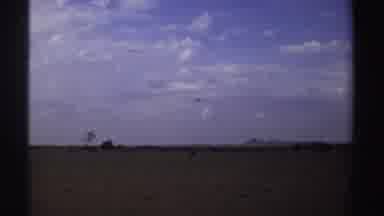 Sudan (1969): View Of Airplane Flying Over Brown Field On A Clear Day