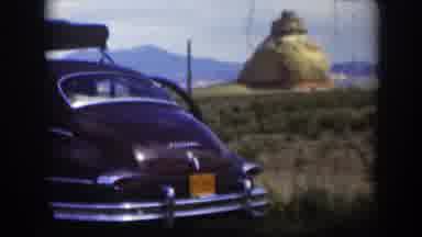 Utah (1951): View Of Brown Car Parked Near Tan Structure On A Sunny Day