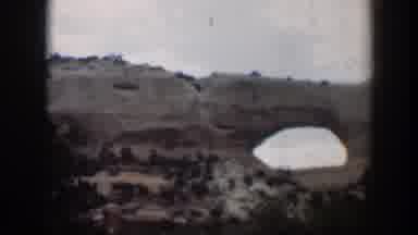 Utah (1951): View Of Green Trees And Tan Mesa Arch On A Cloudy Day