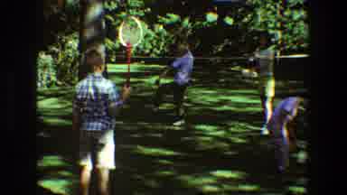 Toledo Ohio (1968): Four People Playing Badminton On Green Grass On A Sunny Day