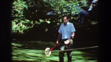 Toledo Ohio (1968): Men Playing Tennis With Rackets In A Field With Lots Of Grass