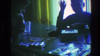 Toledo Ohio (1968): Person Sitting At Table Near Yellow Curtains Waves At Camera