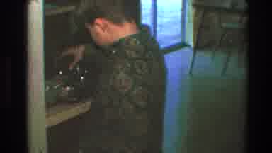 Toledo Ohio (1968): A Young Boy With A Green Shirt Is Organizing Stuff In A Shelf
